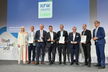 Der Bürgermeister von Denzlingen, Markus Hollemann (Mitte links), und Kämmerer Martin Ziegler (Mitte rechts) bei der Verleihung des KfW Awards Leben 2025 für das zukunftsweisende Nahwärmenetz der badischen Gemeinde.