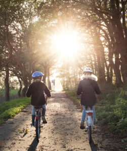 Zwei Kinder fahren mit dem Fahrrad auf einem mit Bäumen gesäumten Weg. Foto: ClickerHappy / pixabay.com