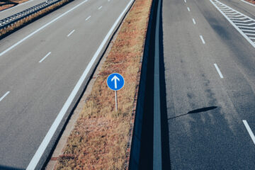 Eine vierspurige Autobahn und in der Mitte ein blaues Verkehrsschild mit Richtungspfeil. Foto: pixabay.com / Alexas_Fotos