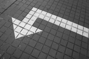 Ein weißer Pfeil auf Pflastersteinen zeigt nach links. Foto: Possessed Photography / unsplash.com