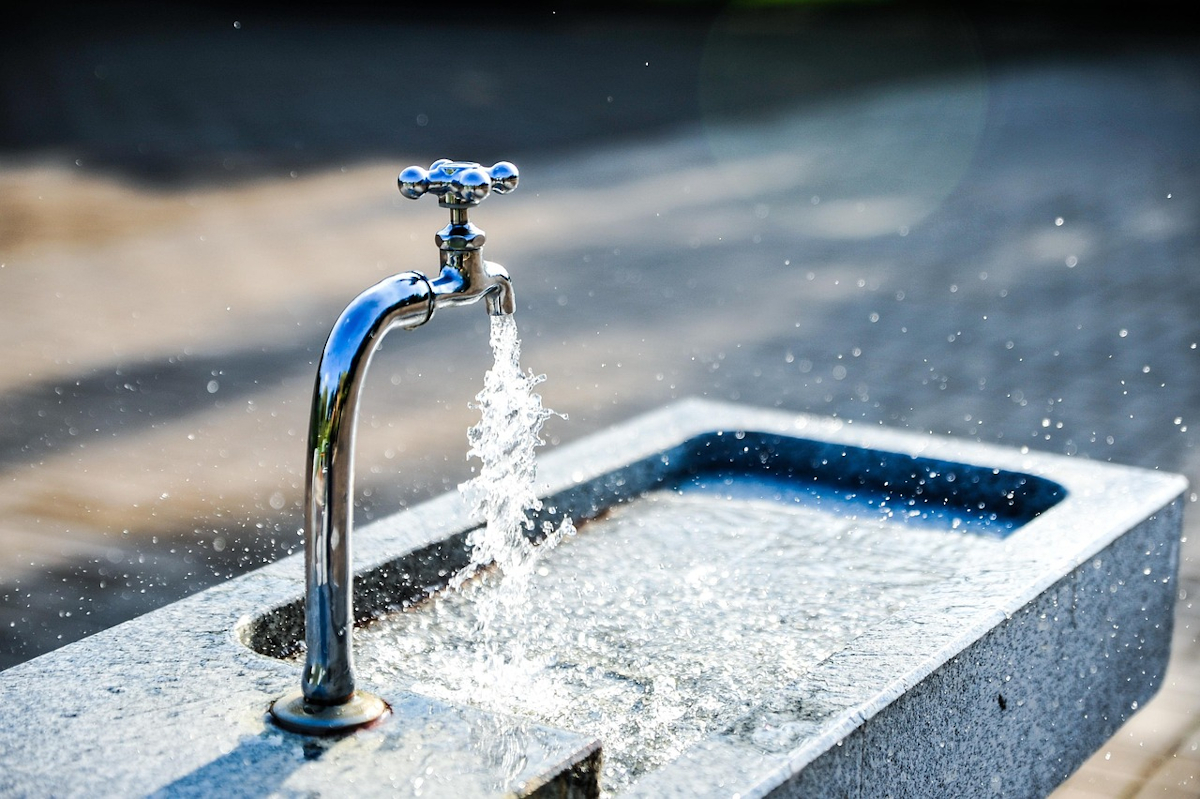 Aus einem Wasserhahn im Freien plätschert sauberes Wasser in ein steinernes Becken. Foto: JonasKIM / pixabay.com